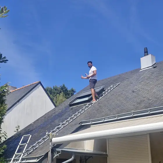 Couvreur de M. Charpentier sur un toit en ardoises à côté d'une fenêtre de toit